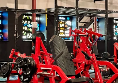 Rote Rogers Athletic Kraftgeräte und Chest Press bei The Church Sports & More Rheine vor farbigen Buntglasfenstern.