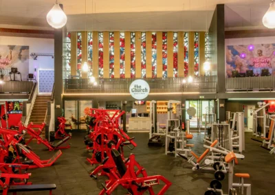 Panorama-Ansicht der Trainingshalle im umgebauten Kirchenschiff von The Church Sports & More Rheine mit umfangreichem Gerätepark und Wandkunst.