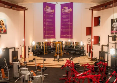 Innenansicht des Fitnessstudios The Church Sports & More in Rheine in einer umgebauten Kirche mit modernen Kraftgeräten und Hantelbereich.